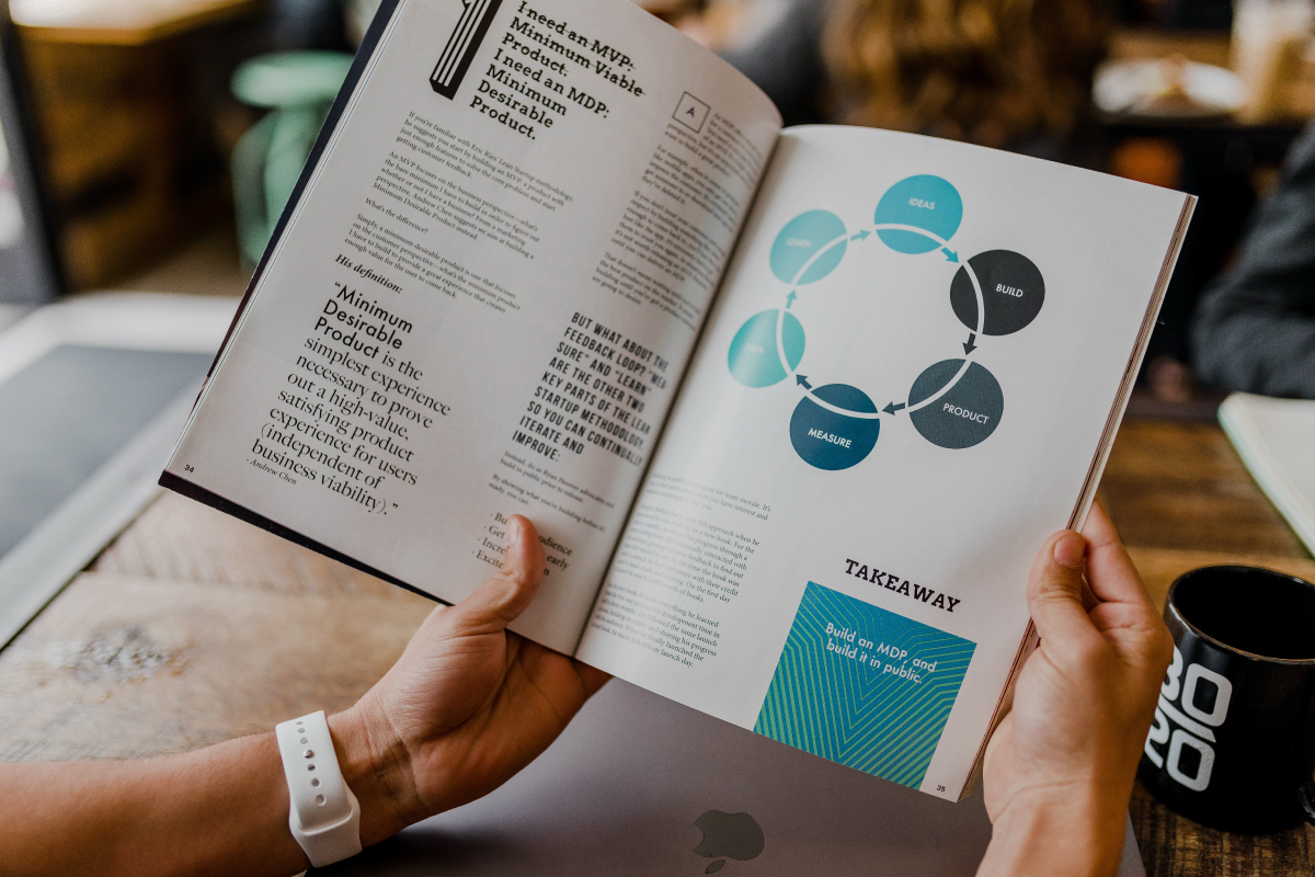 Person Holding Business Book with Teal and Black Graphic of Product Lifecycle