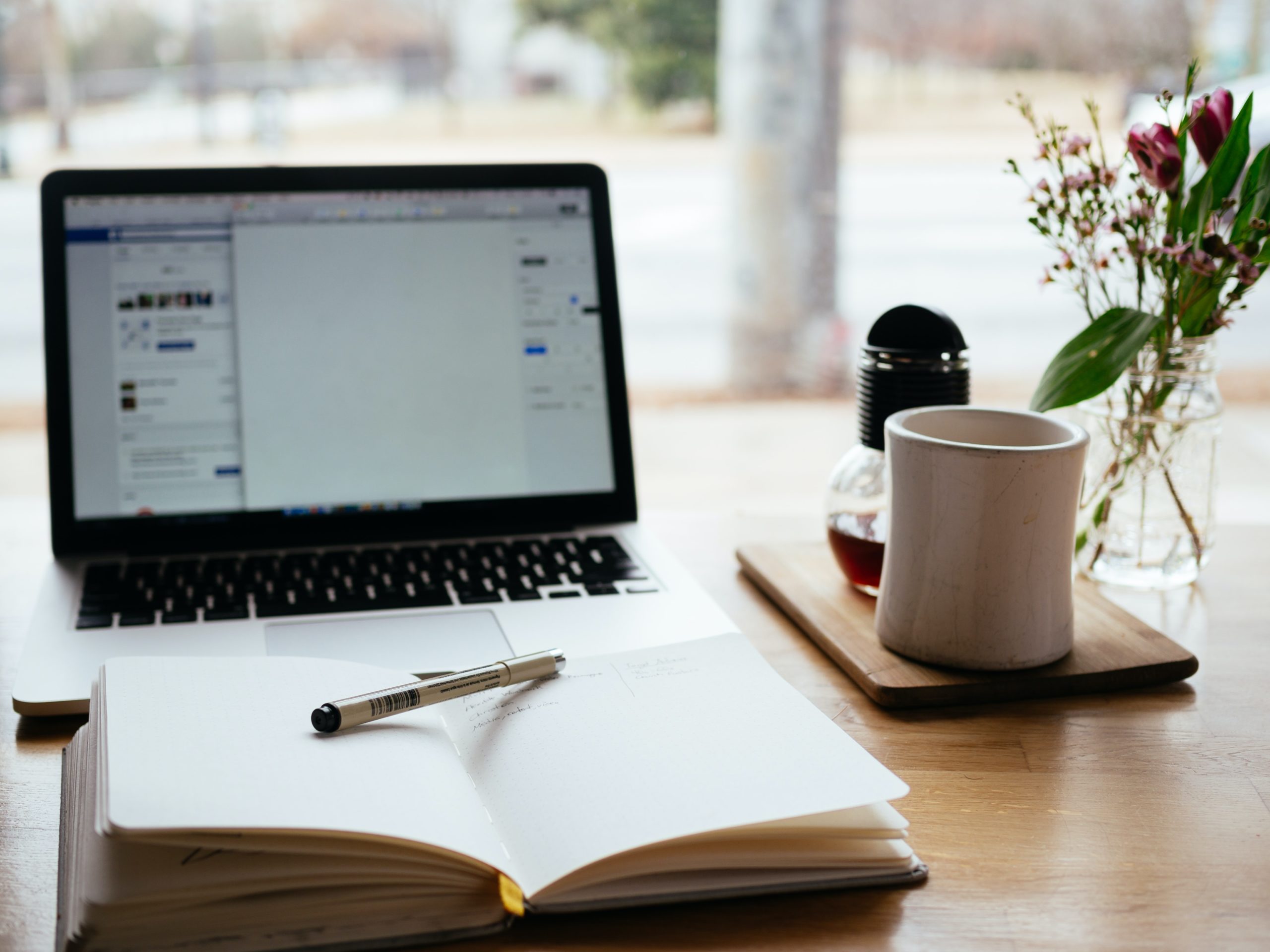 Notebook and Pen in the Foreground, Laptop with Facebook on Screen in Backround