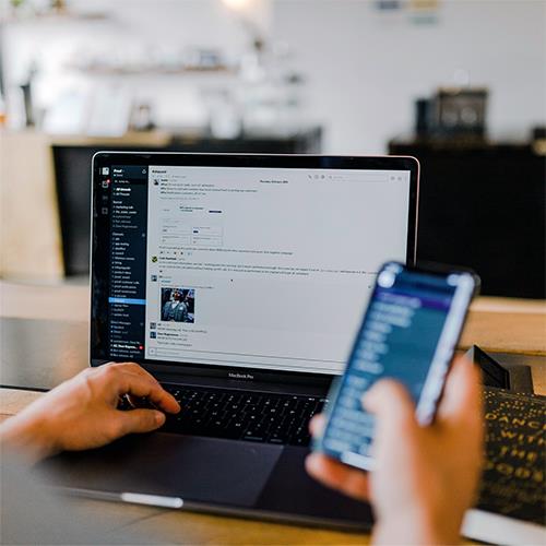 Man Using Black Laptop and Holding Smartphone