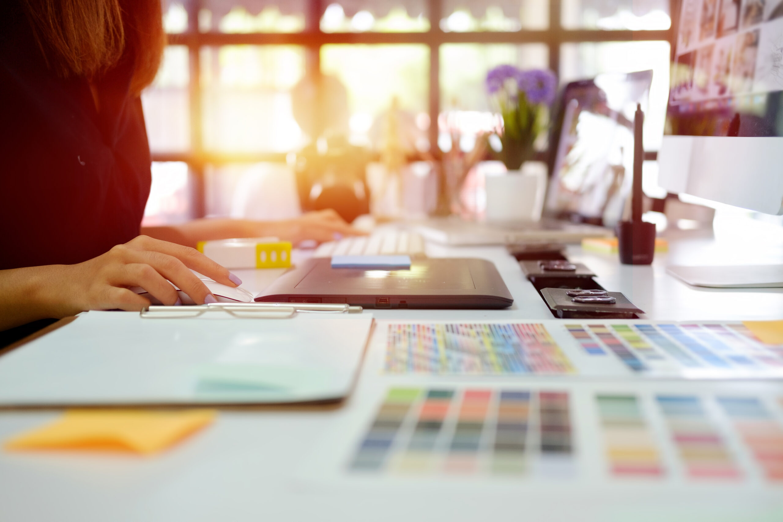 Graphic Designer Sitting at Desk with Logo Design Color Swatches