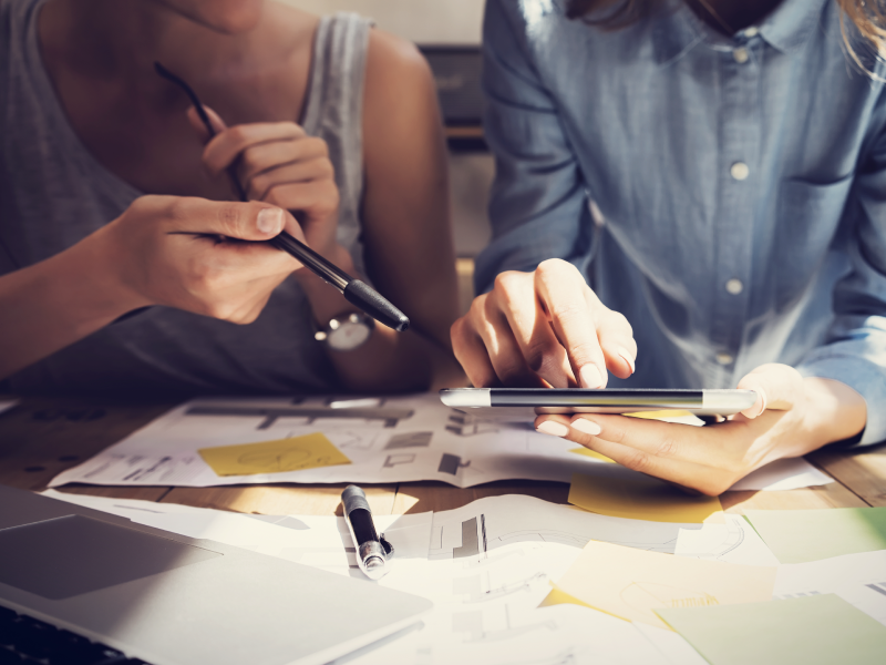 Two People Sitting at Desk with Design Concepts