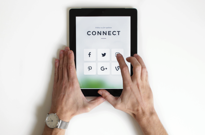 Man's hands holding tablet with social media icons on screen