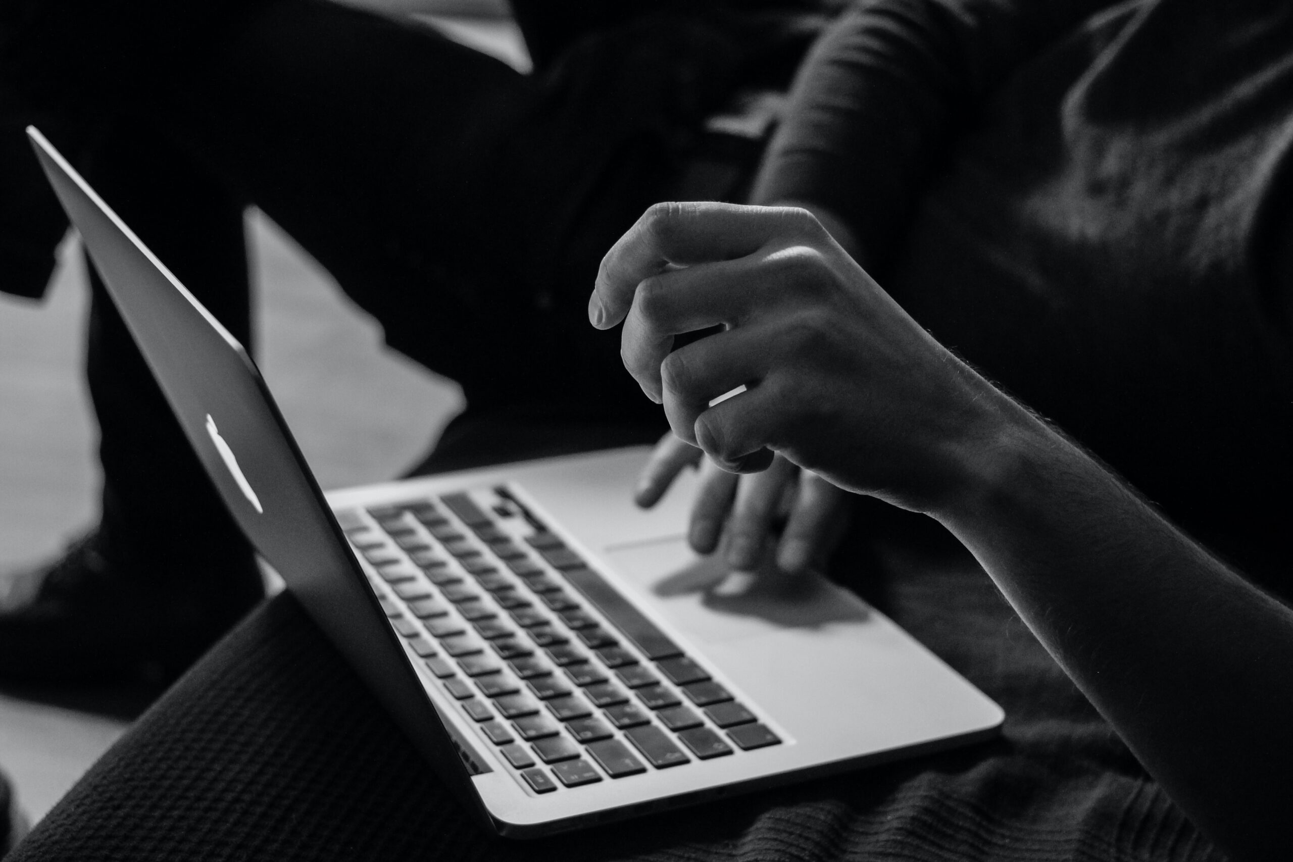 Black and White Photo of Person Using MacBook Laptop