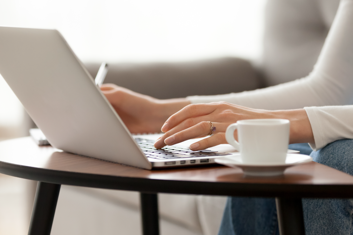 Close up woman using laptop, sitting on sofa, hands typing, writing notes