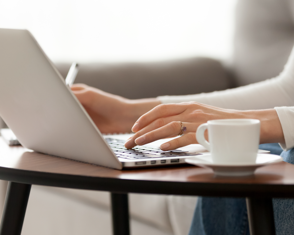 Close up woman using laptop, sitting on sofa, hands typing, writing notes