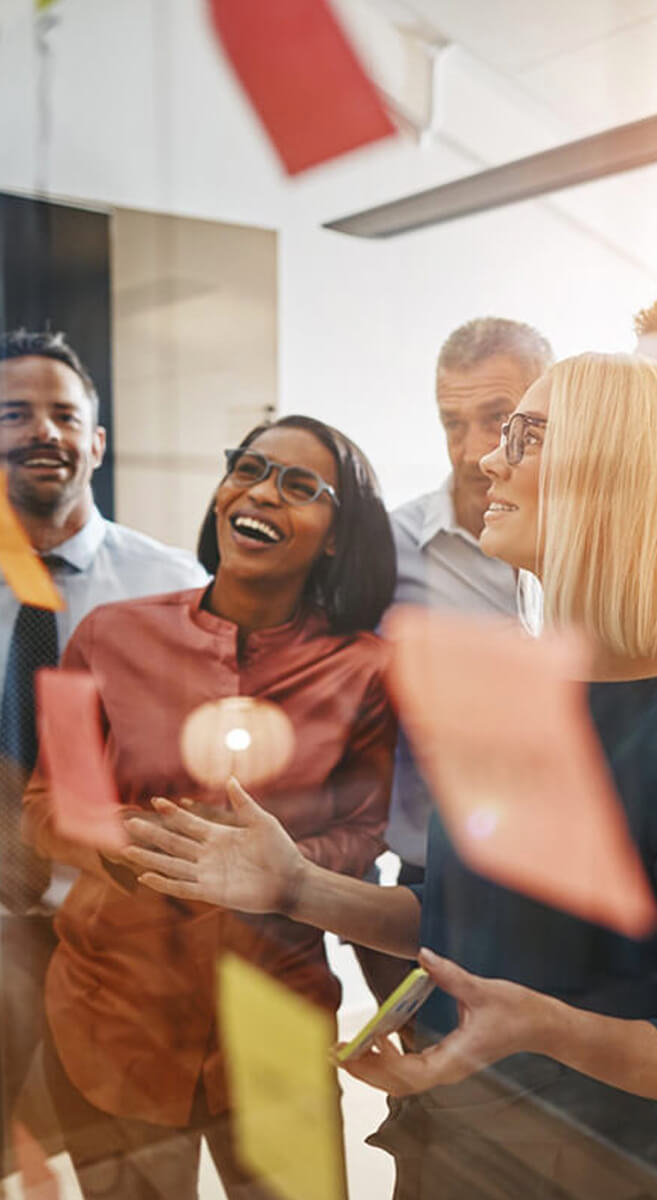 Happy office people staring at a board with sticky notes